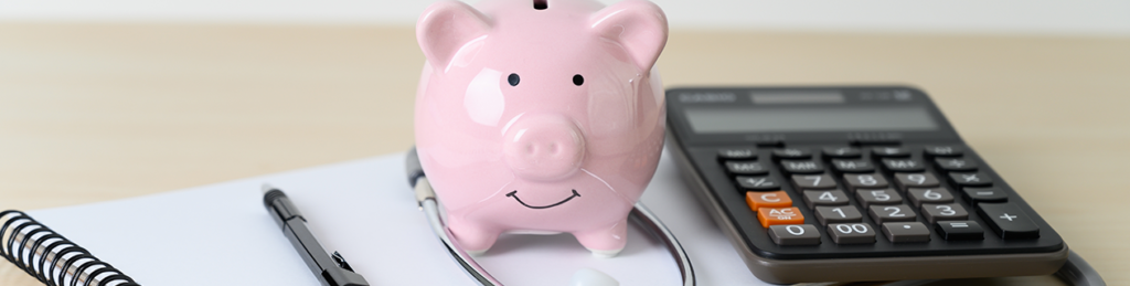 piggy bank, calculator, pen and paper on a desk
