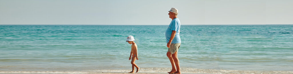 Child and older man walk the beach